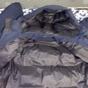 Mörkblå dunjacka från Sail Racing - Säljer en mörkblå dunjacka från Sail Racing med huva och dragkedja. Jackan har en stilren design och är perfekt för kalla dagar. Den är utrustad med Sail Racing Technology för extra värme och komfort.