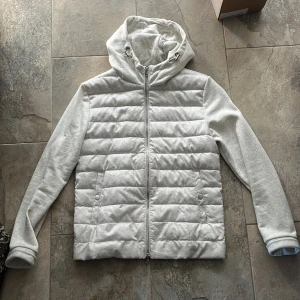 Grå quiltad jacka med huva - Snygg grå jacka med quiltad design och dragkedja framtill. Jackan har en praktisk huva och långa ärmar. Perfekt för våren, köpte den för 2300