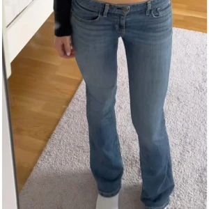 Blå bootcut jeans - Snygga blå bootcut jeans med låg midja. Perfekta för en avslappnad stil. De har en klassisk femficksdesign och en bekväm passform. Knappfickor på rumpan