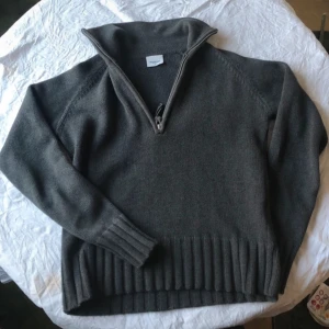 Half zip tröja Boomerang - Säljer en grå stickad tröja från BOOMERANG med dragkedja vid halsen. Tröjan har långa ärmar och ribbstickade muddar vid ärmslut och nederkant. 