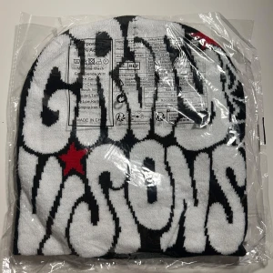 Gravity Visions mössa med stjärna - En stickad mössa från Gravity Visions med svart och vit text på framsidan på andra sidan är det ett vitt spindelnät