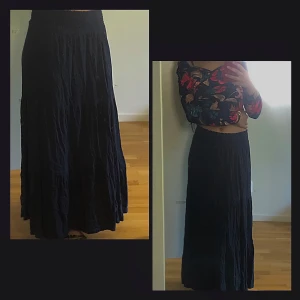 Svart långkjol med volang - Säljer en svart långkjol med volangdetaljer och smock i midjan. Kjolen har en luftig och flowy passform som ger en chill vibe. Perfekt att styla med crop tops eller stickade tröjor. Materialet känns mjukt och bekvämt mot huden.