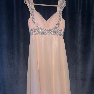 Ljusrosa långklänning med paljetter - Säljer en elegant ljusrosa långklänning med glittrande paljetter runt byst och axelband. Klänningen har v-ringad front, snörning i ryggen och är tillverkad i ett skimrande, lätt material som ger ett lyxigt intryck. Perfekt för bal eller fest! 💖Den är aldrig använd,  Storleken är s men går o spänna in och ut där bak! Priset är ej hugget i sten så de går o diskutera:)! 