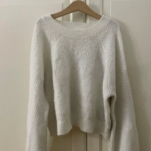 Vit stickad tröja från KappAhl - Mysig vit stickad tröja från KappAhl med rund hals och långa ärmar. Tröjan har en ribbad struktur och är perfekt för kyliga dagar. Passformen är normal och materialet känns mjukt mot huden. Enkel och stilren design som funkar till många olika outfits.Lite smått nopprig, en fläck på ena armen som knappt syns💗
