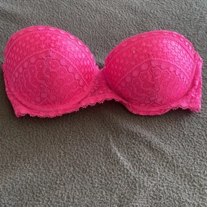 Rosa bh med spets - Snygg rosa bh med spetsdetaljer och vadderade kupor. Toppen är axelbandslös och har en feminin look med vacker spets över hela ytan. 