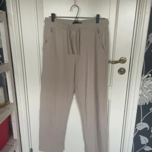 Beiga linnebyxor från 157, storlek S - Snygga och chill beiga linnebyxor från 157 i storlek S. Byxorna har dragsko i midjan, raka ben och fickor på sidorna. Perfekta för en avslappnad look och sköna att bära tack vare det luftiga linnematerialet.