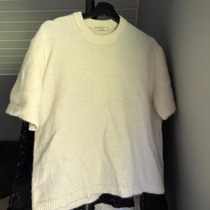 Vit stickad tröja från Gina Tricot - Säljer en vit stickad tröja från Gina Tricot i storlek S. Tröjan har rund hals, korta ärmar och ribbade muddar vid ärmslut och nederkant. Perfekt för dig som gillar enkel och clean stil med mjukt material.💕