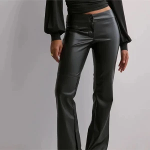 Svarta bootcut byxor i skinnimitation - Nelly lågmidjade skinnbyxor. Använda fåtal gånger. Storlek S 