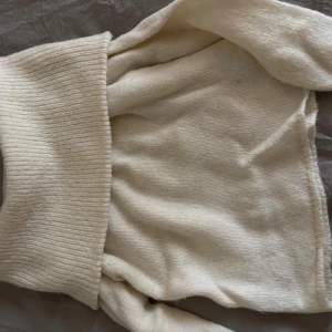 Krämvit polotröja i stickad ull - Säljer en krämvit polotröja med bred ribbad krage och långärmade ärmar. 