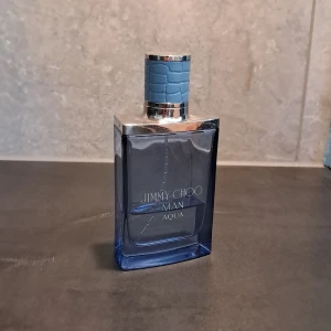Jimmy Choo Man Aqua parfym 20ml - Fräsch och modern herrparfym från Jimmy Choo, Man Aqua. Flaskan är rektangulär i transparent blått glas med silverdetaljer och ett stilrent blått lock med krokodilpräglad yta. Kommer i matchande blå kartong. Volym: 20ml. En Fräsch vatten och citrus doft som funkar året om