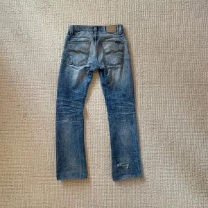 Nudie Jeans - Intressekoll‼️                                                        As feta jeans från nudie modell Slacker Jack. De är välanvända vilket har gett den snygga färgen och de snygga slitningarna. Står storlek 31/36 men passar mig perfekt som är 187 ish. 