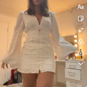 Adoore klänning - Säljer en vit kortklänning med v-ringad hals och långa, vida ärmar från adoore endast använd en gång 