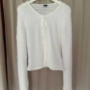 Vit fluffig kofta med knappar - Supermjuk och fluffig vit kofta från Gina Tricot med rund hals och knappar framtill. Långärmad och perfekt för att ge din outfit en mysig vibe. Använd en gång, så i nyskick!!☺️💓