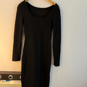 Svart ribbad klänning  - Snygg svart ribbad klänning i storlek S. Klänningen har lång ärm, rundad halsringning och är figurnära med stretchigt material. Perfekt för dig som gillar enkel men stilren look med lite edge.