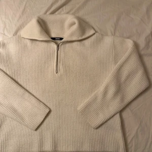 Vit ribbad half zip tröja BikBok - Supermysig vit stickad tröja från BikBok med ribbad struktur och half zip framtill. Tröjan har en bred krage och långa ärmar, perfekt för att hålla sig varm. Passformen är loose och den är enkel att styla till jeans eller leggings.