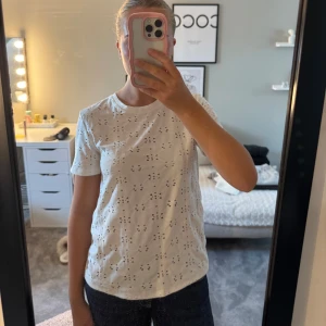 Vit broderad t-shirt från Zara - Snygg vit t-shirt från Zara med korta ärmar och rund hals. T-shirten har ett broderat hålmönster över hela plagget.😍Aldrig använd. 