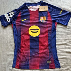 FC Barcelona Lamine Yamal tröja Nike S - Säljer en officiell FC Barcelona matchtröja från Nike med Lamine Yamal och nummer 10 på ryggen. Tröjan är randig i blått och rött med gula detaljer, klubbmärke och sponsorloggor. Tillverkad i lätt och ventilerande Dri-FIT-material, kortärmad och perfekt för fotbollsfans.