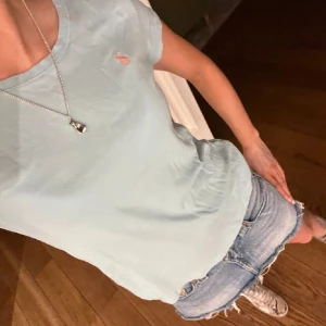 Ljusblå t-shirt från Ralph Lauren - Snygg ljusblå t-shirt från Ralph Lauren med klassisk rund hals och korta ärmar. Diskret broderad logga i orange på bröstet. Mjuk och skön bomull som passar perfekt till jeans eller shorts. Enkel och stilren design som är lätt att matcha.