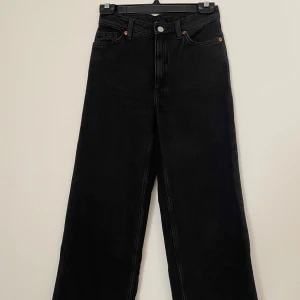 Svarta wide jeans från Monki - Svarta jeans från Monki med hög midja och breda ben. Klassisk femficksmodell med knapp och dragkedja framtill. Jeansen är i kraftig denim och har en stilren look som passar till allt. Nypris 499kr