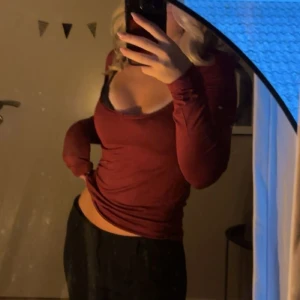 Vinröd topp Nelly - Säljer en vinröd långärmad topp med djup v-ringning och figurnära passform. Toppen har en enkel och stilren design, perfekt att matcha med jeans eller kjol. Materialet är mjukt och stretchigt för en bekväm känsla.