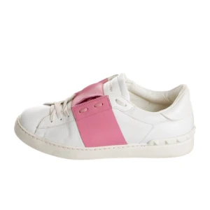 Valentino Open sneakers med rosa detalj - Säljer ett par vita Valentino Open sneakers med bred rosa läderdetalj över snörningen. Skorna har rund tå, platt sula och ikoniska nitar baktill på hälen. Perfekta för dig som vill ha en stilren men ändå färgglad look.