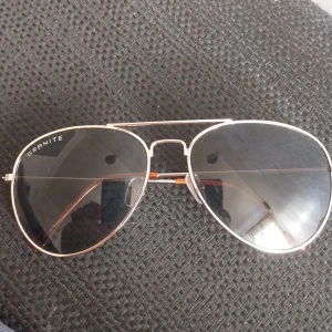 Aviator solglasögon från Granite - Snygga aviator solglasögon från Granite med tunna silvriga metallbågar och mörka glas. Klassisk pilotmodell som ger en cool look. Passar perfekt för soliga dagar.Går att frakta men köparen betalar frakt