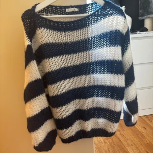 Randig stickad tröja från Design by Si - Säljer en grovstickad tröja från Design by Si med breda blå och vita ränder. Tröjan har lång ärm och en luftig, oversized passform. Perfekt för lager-på-lager och en avslappnad stil. Och aldrig använd 