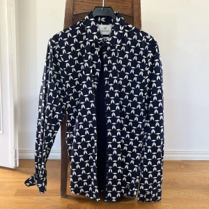 Mönstrad skjorta från Scotch & Soda - Snygg mörkblå skjorta från Scotch & Soda med vitt grafiskt mönster. Skjortan har långa ärmar och klassisk krage, perfekt för dig som vill sticka ut lite extra. Tillverkad i mjuk bomull för en skön känsla.