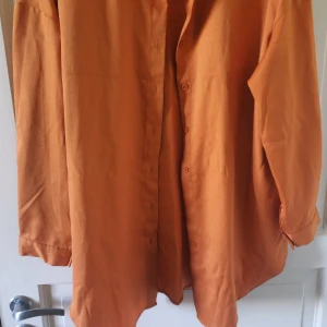 Orange skjorta från SHEIN - Säljer en orange skjorta från SHEIN i storlek L. Skjortan har klassisk krage, knäppning framtill och långa ärmar. Perfekt för dig som gillar en enkel men färgstark stil.