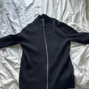 Mörkblå  stickad tröja med dragkedja från Jack&jones - Säljer en mörkblå  stickad tröja från Jack&jones med hel dragkedja framtill. Tröjan har lång ärm, hög krage och är ribbstickad för en snygg och stilren look.