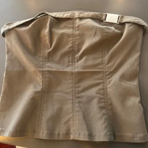 Militärgrön tubtopp med bälte från Urban Outfitters (Silence + Noise) - Säljer en khakigrön tubtopp från Urban Outfitters i viscosematerial. 🪖Toppen har ett dekorativt bälte upptill och en enkel, stilren design utan ärmar. Perfekt look till sommaren! Aldrig använd med lapp kvar då den är lite för stor, stl L men tycker den passar mer som M + stretchig! 