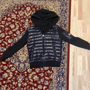 Moncler Cardigan  - Snygg marinblå cardigan från Moncler med glansig framsida, huva och hel dragkedja. Fin och stickad matieral. Perfekt för våren! Inga defekter! M men passar mest S. 
