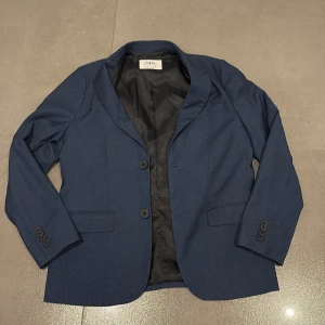 En mörkblå kavaj - En snygg mörkblå kavaj med en riktigt bra skick. Den är väldigt skön att ha på sig och samtidigt enkel. 