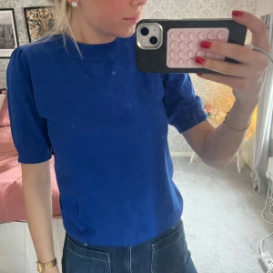 Kornblå stickad topp från Saint Tropez - Säljer en kornblå stickad topp från Saint Tropez. Modellen har korta ärmar med lätt puff och ribbade muddar vid ärmslut och nederkant. Perfekt till jeans eller kjol för en snygg look. Materialet är mjukt och stretchigt.