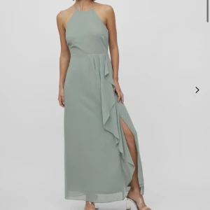 Ljusgrön långklänning - Super fin ljusgrön långklänning med halterneck, volangdetalj framtill och hög slits. Perfekt för balen. Endas använd en gång och inga tecken på användning, pris kan diskuteras💕