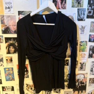 Svart långärmad topp med twistdetalj från Chiara Forthi - Säljer en svart långärmad topp från Chiara Forthi Milano. Toppen har en snygg twistdetalj framtill som ger en draperad effekt och en feminin v-ringning. Perfekt att styla till olika outfits.