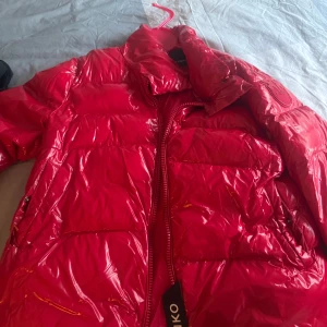 Röd pufferjacka från Pinko - Säljer en glansig röd pufferjacka från Pinko med dragkedja framtill och stora fickor. Jackan har hög krage och lång ärm, perfekt för kyligare dagar. Snygg och trendig modell som sticker ut. Storlek M på jackan, köptes för 3500 säljer 1700 men pris kan diskuteras 