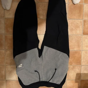 Svarta och grå mjukisbyxor från Nike - Säljer ett par mjukisbyxor från Nike i svart och grått. Byxorna har dragsko i midjan och en liten vit Nike-logga på vänster sida. Perfekta för chill eller träning. Bara snörena som gått sönder i tvätten