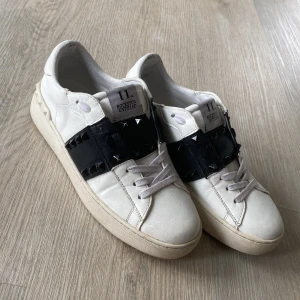Valentino open skor - Snygga vita sneakers från Valentino med svarta detaljer och nitar. Skorna har en klassisk design med snörning och en bekväm sula. Perfekta för att ge din outfit en stilren touch. Skick 8/10 tecken på användning finns hör  av er vid frågor eller intresse.