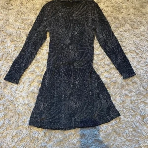 Festlig glitter klänning - Säljer denna fina klänning i storlek S. Den är svart med ett vackert glittrigt stjärnmönster och har långärmad design. Perfekt för festliga tillfällen. 🪩  ✅ Använd endast vid 5 tillfällen ✅ Bra skick, inga skador eller fläckar ✅ lösare passform  Skicka gärna ett meddelande vid frågor. Kan skicka flera bilder, eller bilder hur den ser ut på ifall man vill! ✨  (Pris kan diskuteras, buda gärna!)