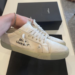 Saint Laurent skor - Tjena, säljer nu mina beige/vita saint Laurent skor. Skorna är i bra skick men en liten defekt under skon, därav priset! Skriv gärna om ni har några funderingar🤩💭