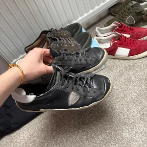 Philippe models  - Svarta sneakers från Philippe Model med vit häl och grå detalj på sidan. Skorna har snörning och en platt sula. Tillverkade i skinn med en klassisk, rund tå och diskret logga på sidan.