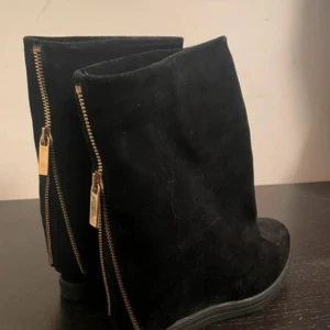 Svarta boots med dragkedja - Säljer ett par svarta boots i mocka med grov guldfärgad dragkedja baktill. Storlek 39