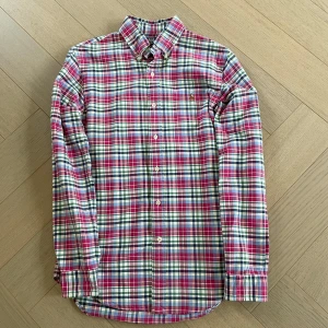 Rutig skjorta från Polo Ralph Lauren - Säljer en klassisk rutig skjorta från Polo Ralph Lauren i slim fit. Skjortan har långa ärmar, knappar framtill och broderad logga på bröstet. Färgerna är röd, grön, blå, gul och vit. Perfekt för dig som gillar tidlös stil!