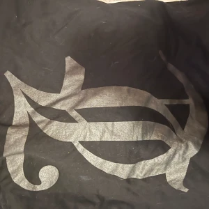 Svart t-shirt Juicy Couture med tryck - Svart t-shirt från Juicy Couture med stort, glansigt silvertryck framtill. Klassisk rund halsringning och korta ärmar. Skön och mjuk bomullskvalitet som passar perfekt till jeans eller kjol. Snygg statement-tee för dig som gillar att sticka ut.