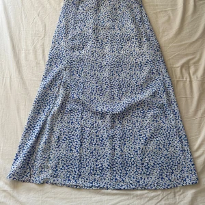 Blommig blå långkjol från SHEIN - Supersöt långkjol från SHEIN med blå botten och vitt blommönster. Kjolen har en flowy passform och är perfekt för dig som gillar en feminin och somrig stil. Lätt material som känns skönt mot huden.