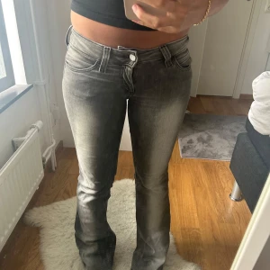 Low waist jeans från cheap Monday  - Säljer ett par grå jeans med bootcut passform och snyggt tvättad look. Jeansen har klassiska fem fickor, låg midja och dragkedja. Materialet är mjukt och stretchigt för skön passform. Perfekta för dig som gillar en avslappnad stil.
