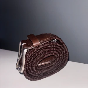 Brunt flätat bälte  - Snyggt brunt bälte med flätad design och detaljer i brunt skinn. 