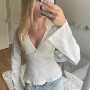 Tie top från Gina Tricot XS - Supersnygg vit omlottopp från Gina Tricot i storlek XS. Toppen har v-ringning, långa armar och knytning i ryggen. I väldigt bra skick! Säljer då den inte kommer till användning ❤️