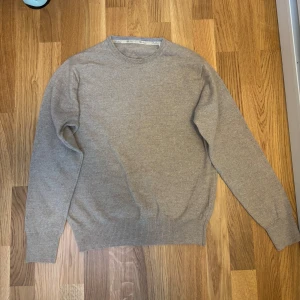Beige stickad tröja från Stenströms - (SITTER SOM EN SMALL pga krympt i tvätten) Säljer en stilren beige stickad tröja från Stenströms i storlek L. Tröjan har rund halsringning, ribbade muddar och förstärkta armbågslappar i samma färg. Perfekt för lager-på-lager och passar till både jeans och chinos. 